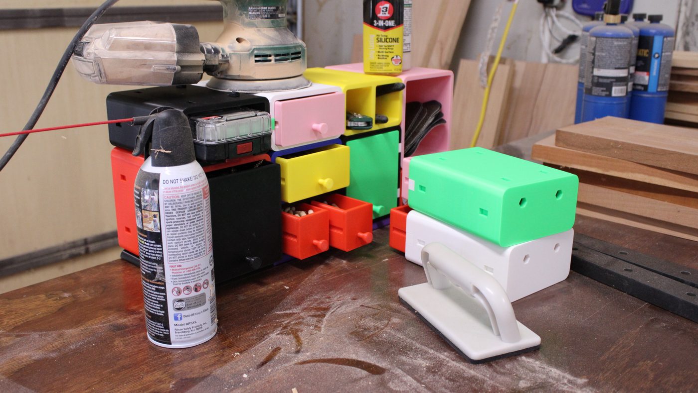 A stack of modular printed drawers and cubbies in mixed colors, in use on a workshop bench
