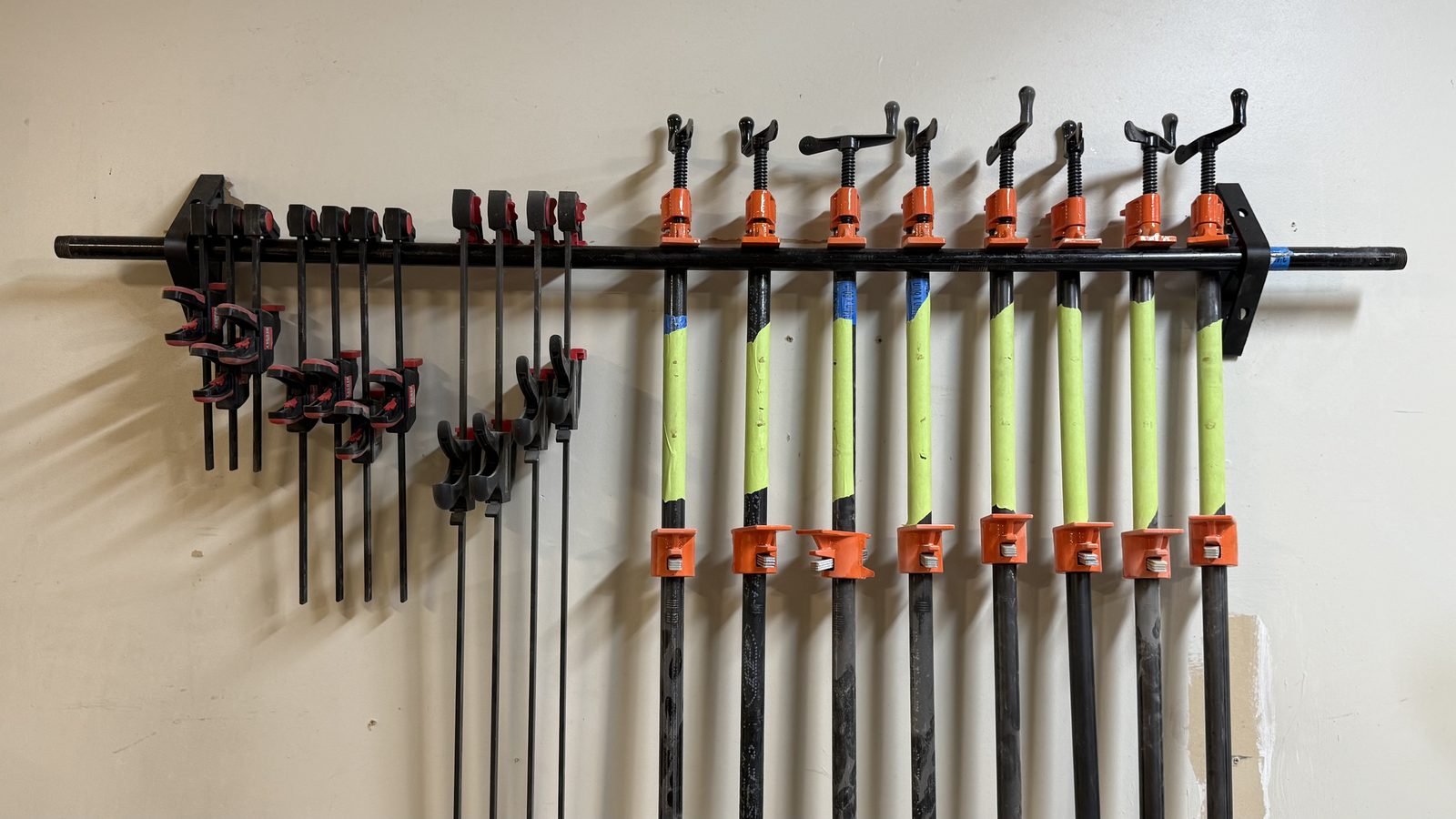 PipeHold pipe rail holding a full row of pipe clamps, bar clamps, and quick-grip clamps