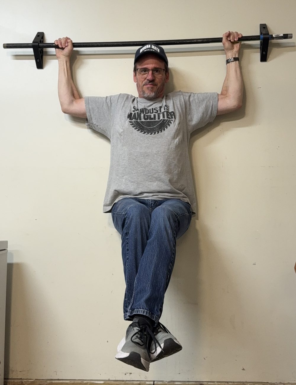 A grown man hanging from the PipeHold rail, feet off the ground, both brackets holding